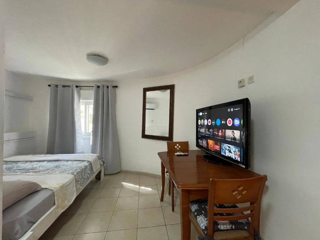 埃拉特Eilat Beach House的一间卧室配有一张床和一张书桌及一台平面电视