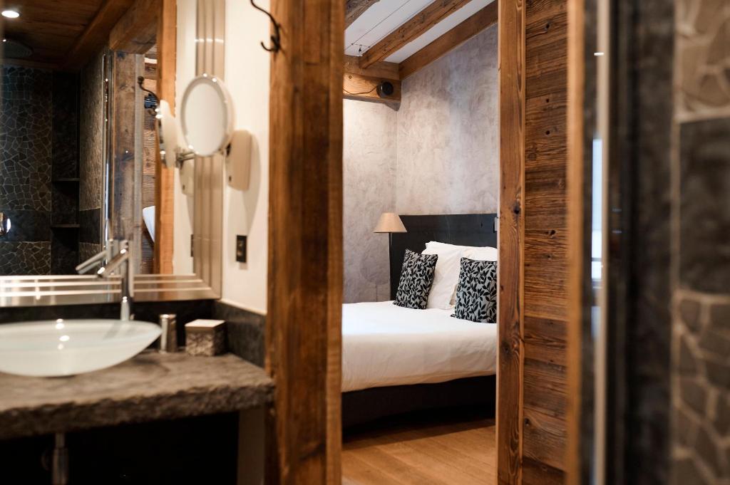 蒂涅Les Suites – Maison Bouvier的一间带水槽的浴室和一张位于客房内的床