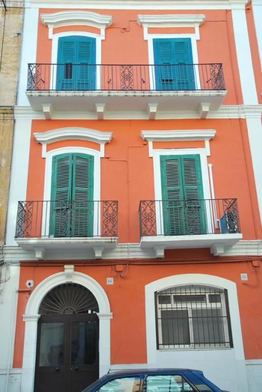巴里Appartamento Aurora的一座橙色的建筑,设有蓝色的窗户,前面设有停车位