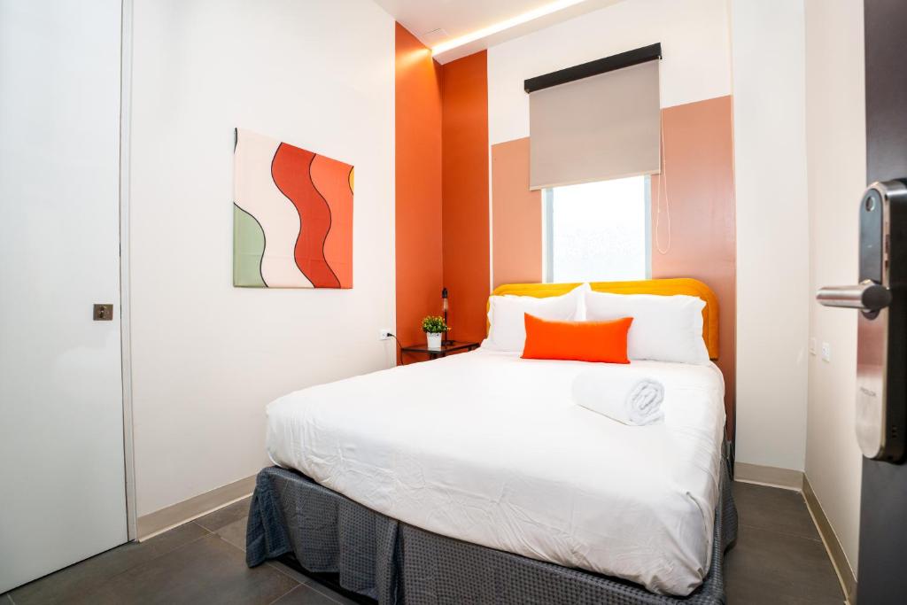 圣胡安Somos Hotel的一间卧室配有一张白色大床和橙色床头板