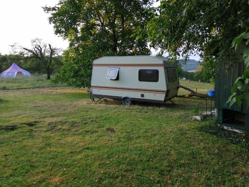 ChâtelneufLa Tanière de la Louve的停在帐篷旁边的田野上的白色大篷车