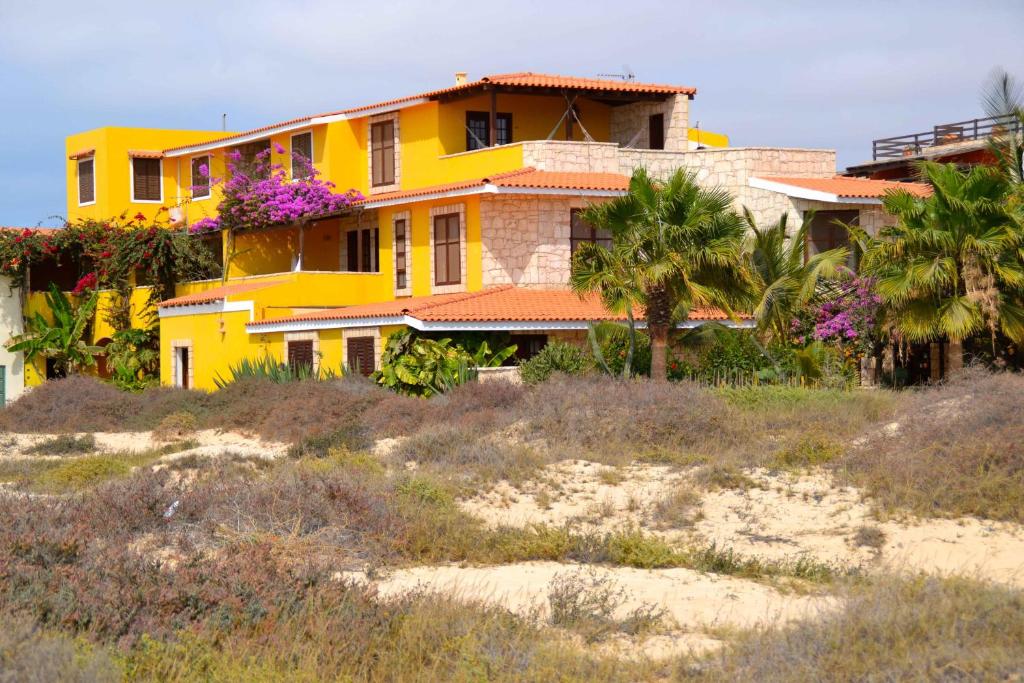 萨尔雷Guest House Orquidea的棕榈树海滩上的黄色房子