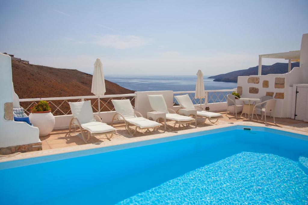 阿斯提帕莱亚镇托拉丽亚精品酒店的一个带白色椅子的游泳池和一个蓝色的游泳池