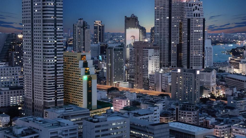 曼谷Holiday Inn Bangkok Silom, an IHG Hotel的城市天际线,夜晚有许多高楼