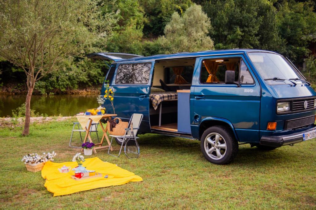 采蒂涅Vanlife Montenegro Camper Van and 2 Bikes的停在草地上的蓝色货车,有桌子