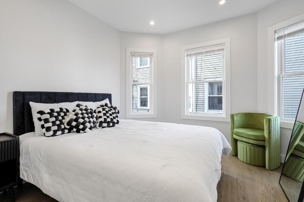 萨默维尔3BR2Bth MIT Harvard TD Garden BOS 2 Parking Spaces的一间带床和绿色椅子的白色卧室