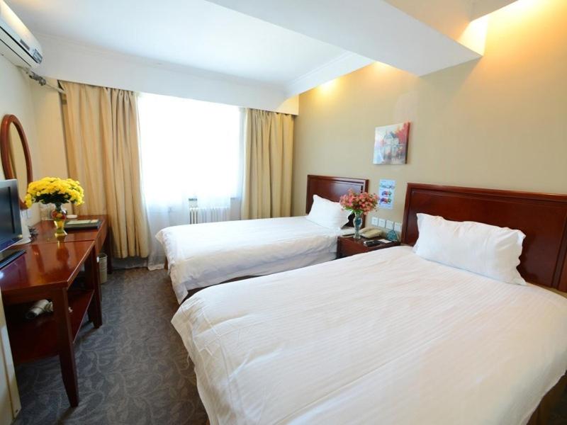 松江格林豪泰上海车墩影视乐园快捷酒店的酒店客房设有两张床和电视。