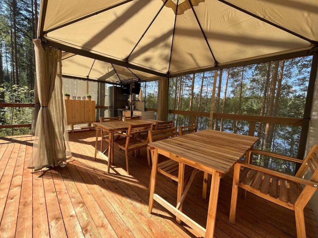 萨翁林纳Alaska Glamping Linnansaari的木制甲板上配有桌椅的帐篷