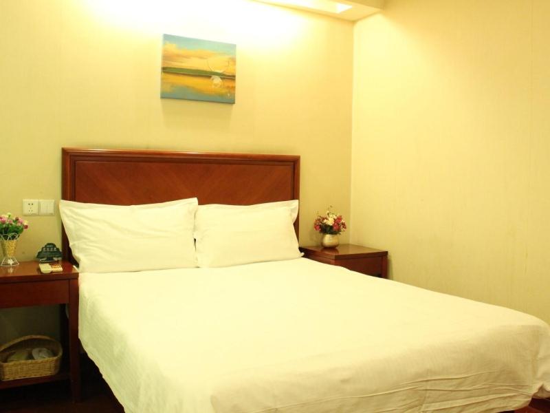 滨海新区格林豪泰天津市大港区石化路商务酒店的一间卧室配有一张带白色床单的床和两张桌子