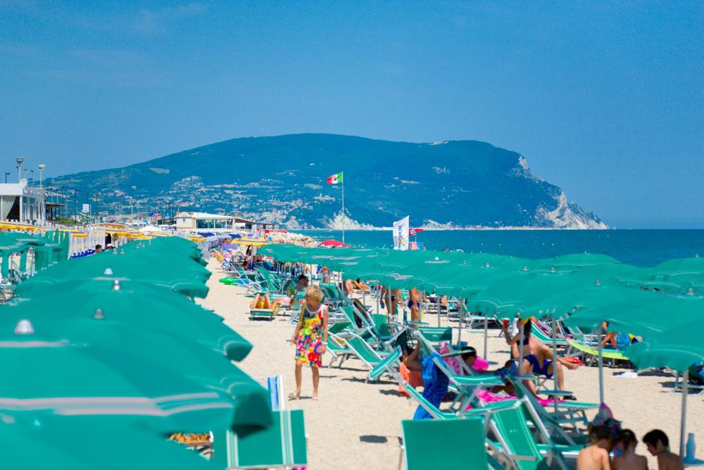 雷卡纳蒂港Villaggio Turistico Internazionale的一群人在海滩上,沙滩上摆放着绿色的沙滩椅