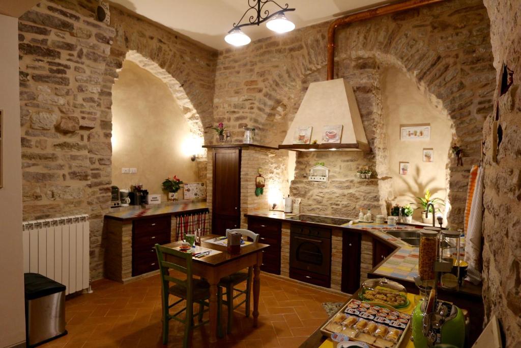 阿西西拉卡西纳科罗拉塔旅馆的厨房设有石墙和桌椅