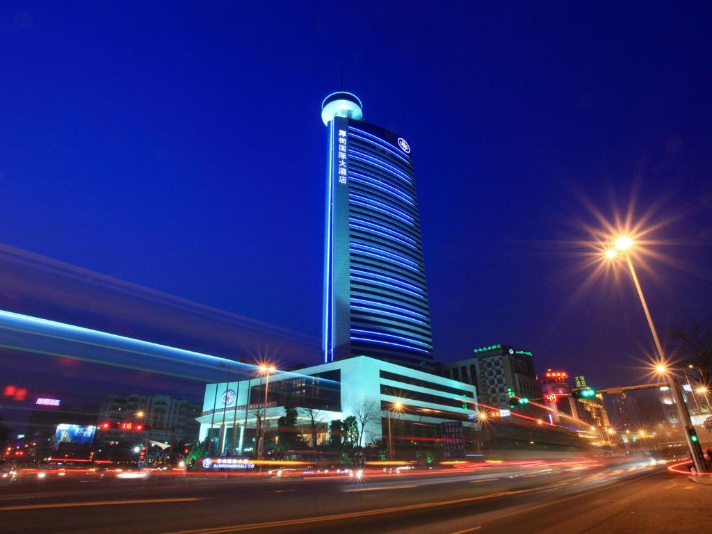 东莞HJ International Hotel的夜晚高大的建筑,有街道和街道的灯光