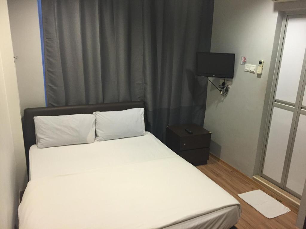 新加坡Hotel Conforto的一张带白色床单的床和客房内的电视