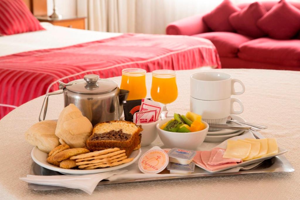 圣地亚哥圣地亚哥蒙特卡洛酒店的床上的早餐食品和饮料托盘