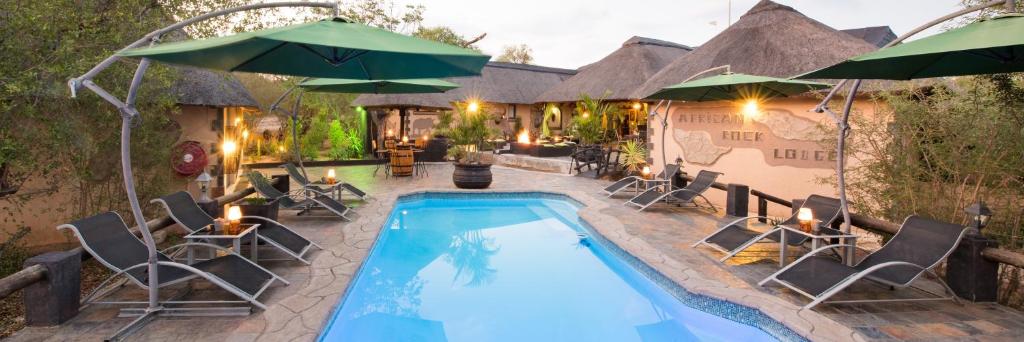 侯斯普瑞特非洲岩旅舍的房屋旁的游泳池配有椅子和遮阳伞