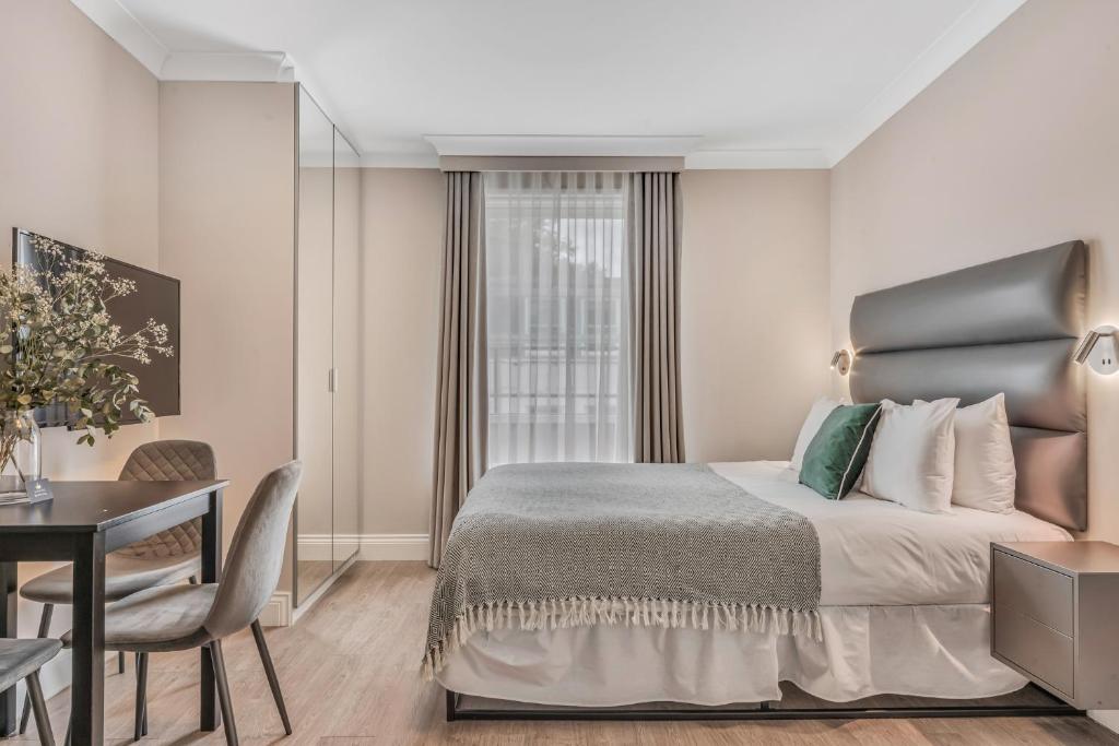 伦敦Cleveland Residences Paddington的一间带床、书桌和窗户的酒店房间