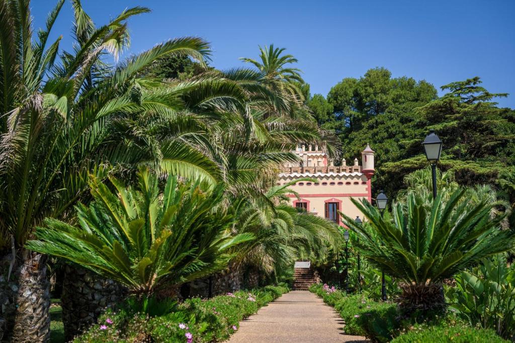 Xerta雷蒂罗别墅酒店 的棕榈树环绕的粉红色房子和小径