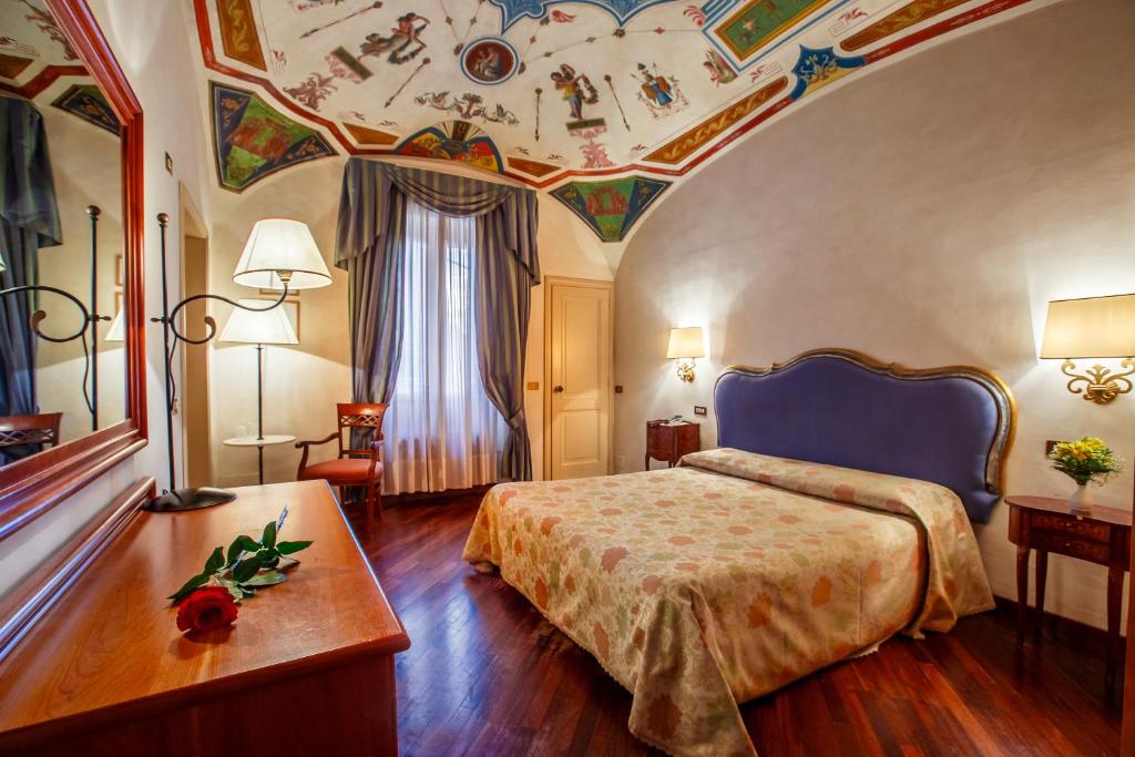 佩鲁贾福尔图纳酒店的酒店客房设有一张床和天花板绘画作品
