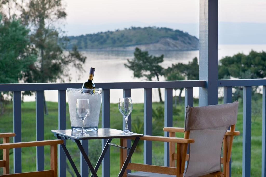 奥马斯帕纳吉亚斯Serenity Estate的阳台上的桌子上放有一瓶葡萄酒和两杯酒