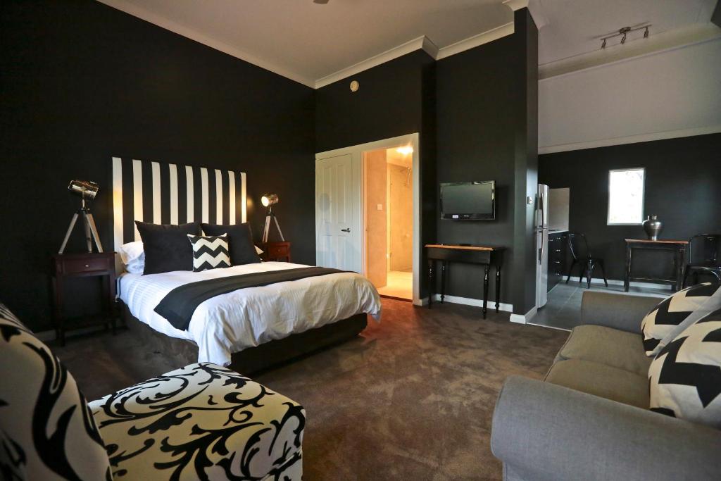 Currency Creek围场溪酒厂别墅的卧室拥有黑色的墙壁,配有一张床和一张沙发