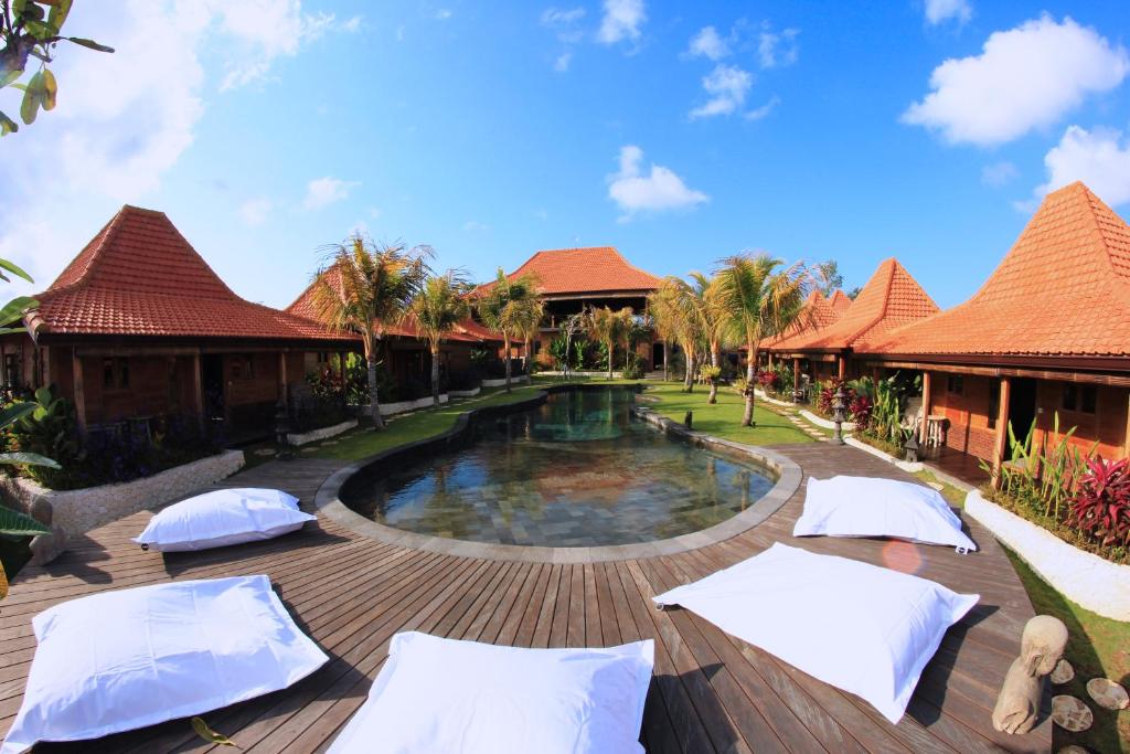 乌鲁瓦图瑜伽寻找者巴厘岛度假村的一个带游泳池和带遮阳伞的甲板的度假村