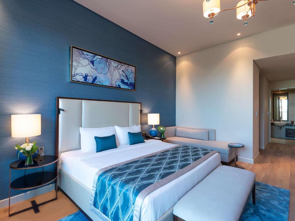 迪拜Rixos The Palm Hotel &amp; Suites - Ultra All Inclusive的卧室里有一张大床，墙壁是蓝色的