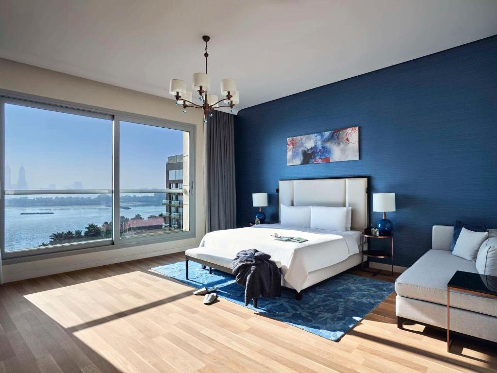 迪拜Rixos The Palm Hotel &amp; Suites - Ultra All Inclusive的蓝色的卧室设有床和大窗户