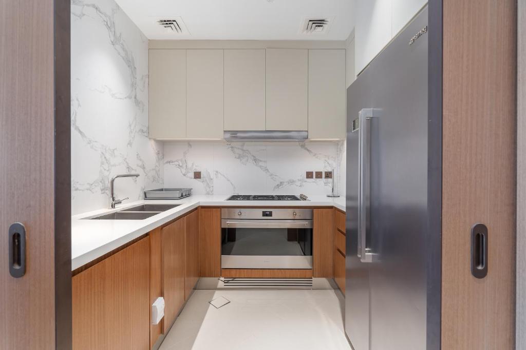 迪拜Address Residences Dubai Opera - Burj Khalifa City Views 1, 2, &amp; 3-Bedroom Apartment 1 minute walk to Burj Khalifa, Dubai Mall, Dubai Fountain by Heaven Crest的配有木质橱柜和不锈钢冰箱的厨房