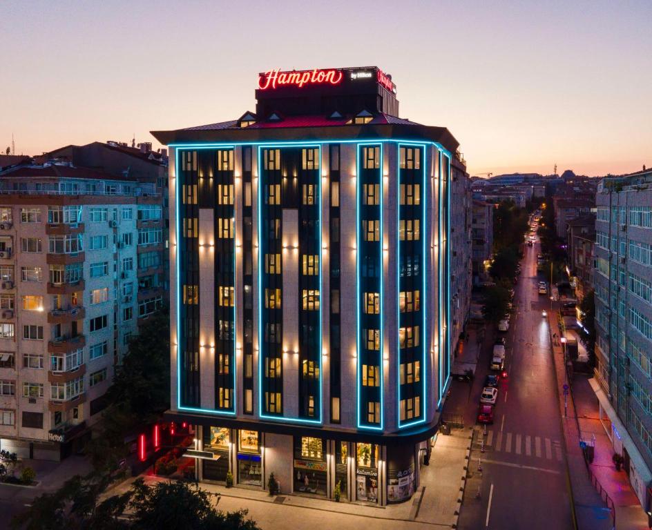 伊斯坦布尔Hampton By Hilton Istanbul Merter的上面有 ⁇ 虹灯标志的建筑