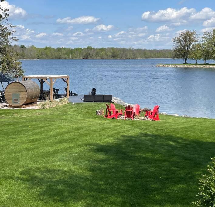 Long SaultSt Lawrence Waterfront Home的坐在湖边草地上的一组椅子