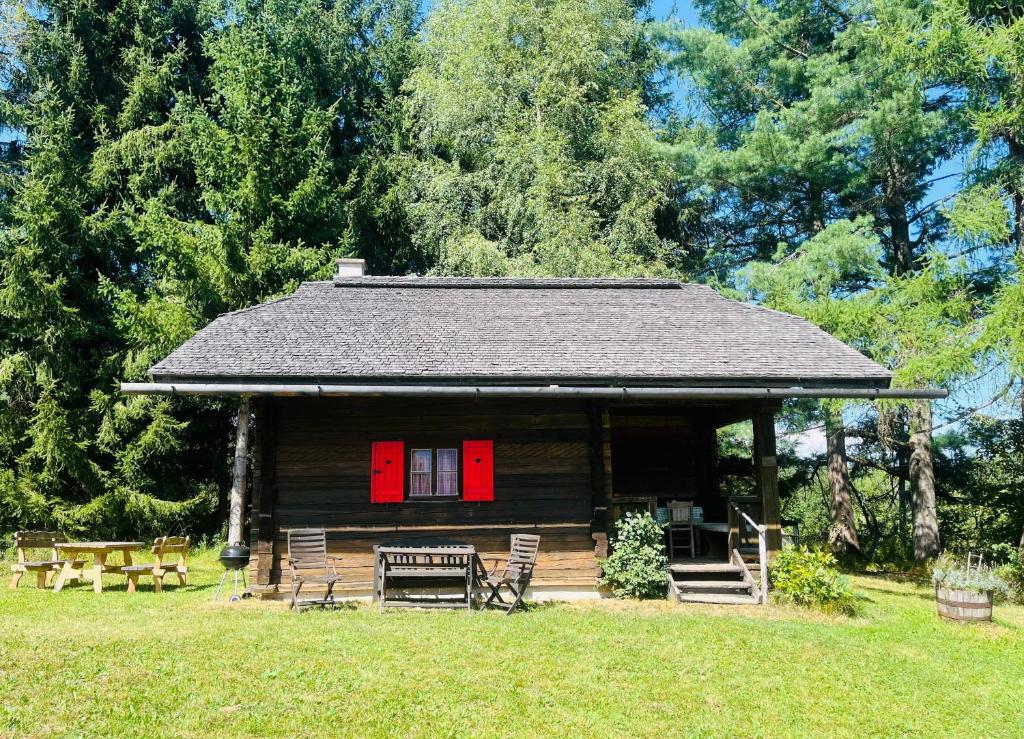 雷丹尼茨恩Cozy Log Cabin near Faaker See的小木屋,设有红色的门和椅子