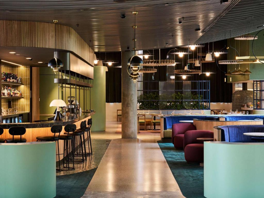 墨尔本ibis Styles Melbourne Airport的餐厅设有酒吧和桌椅