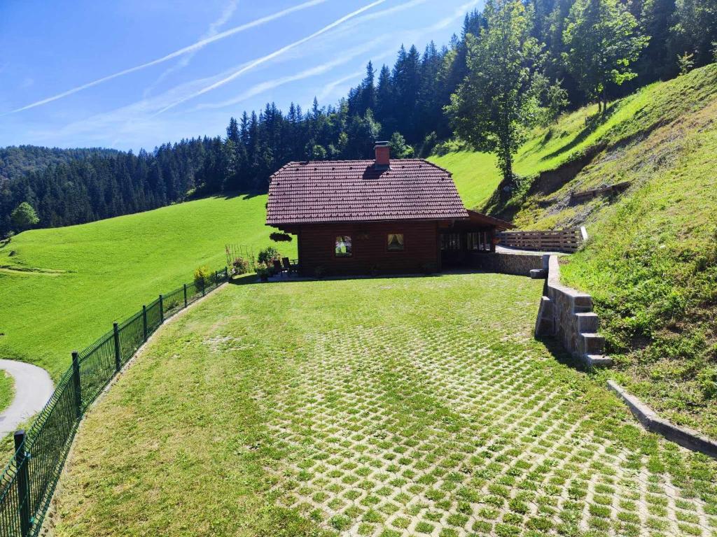 卢斯Počitniška hišica Rogatec - Holiday Cottage Rogatec的一座小房子,位于一座带草地的山丘上