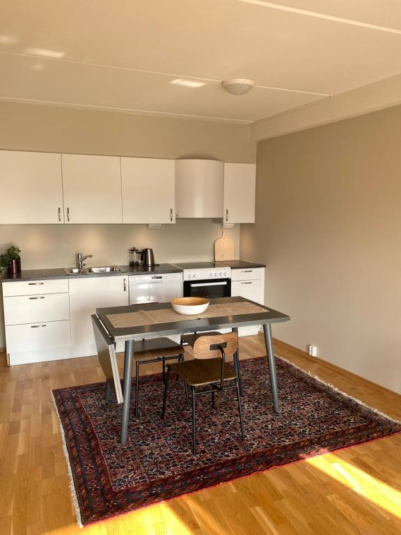 巴杜弗斯Modern apartment in Bardufoss Center - two bedrooms, garage, terrace的厨房配有桌子和两把椅子,铺在地毯上