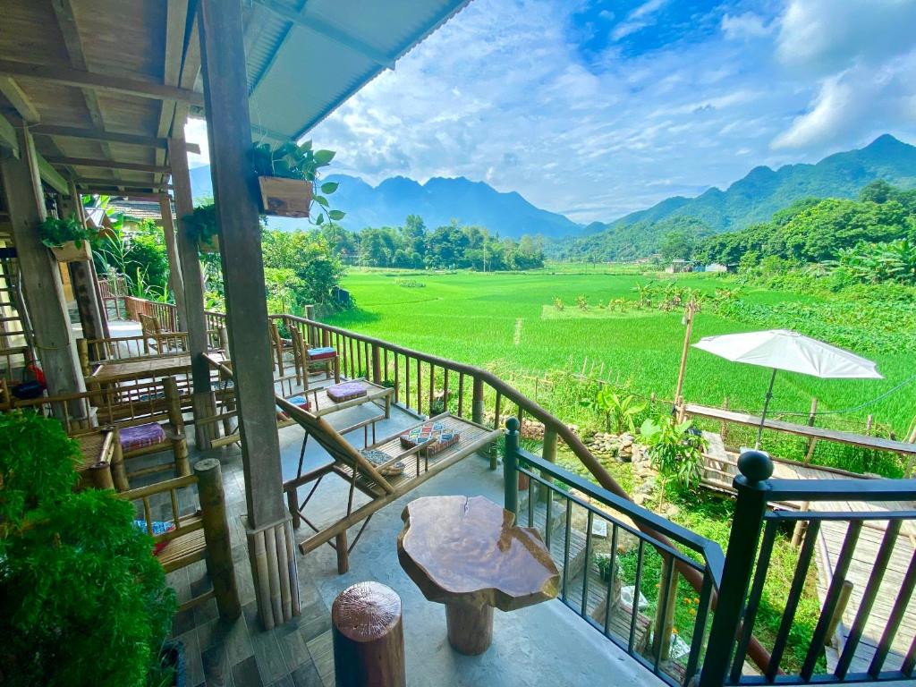 枚州县Meadow Mai Chau Homestay的一个带桌椅的度假村阳台