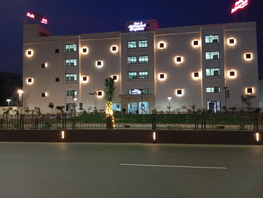 艾哈迈达巴德Hotel Ashray Inn Express的一座大建筑,前面有棕榈树