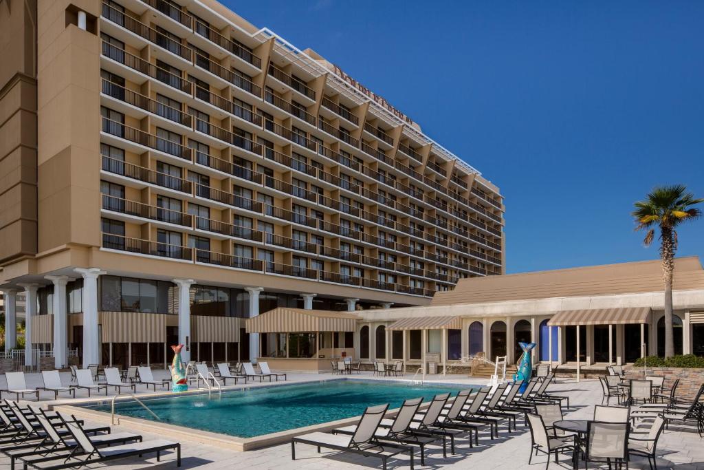 杰克逊维尔佛罗里达州杰克逊维尔河滨希尔顿逸林酒店的一座带游泳池和椅子的酒店和一座建筑