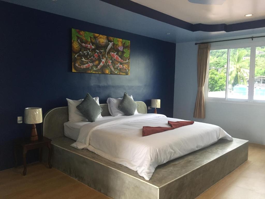 涛岛兄弟姐妹酒店的一间卧室配有一张带蓝色墙壁的大床
