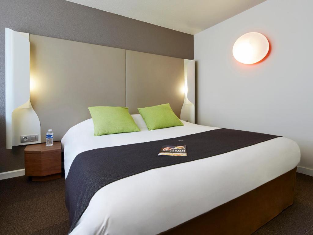 尚布雷莱图尔尚布雷莱图尔南钟楼旅行时光酒店的一间卧室配有一张大床和两个绿色枕头