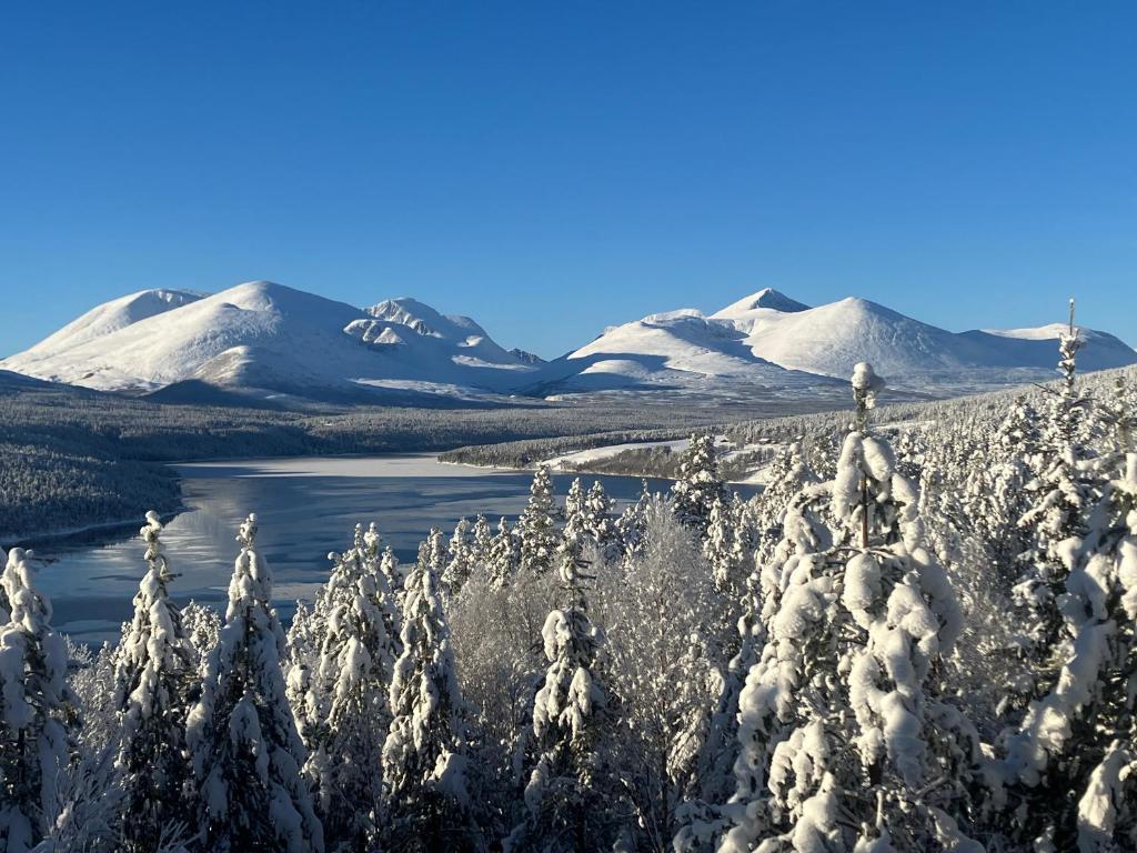 AtnfossRondane - Øvre Nordli Sollia Friluftsliv的积雪覆盖的山脉,积雪覆盖的树木和湖泊