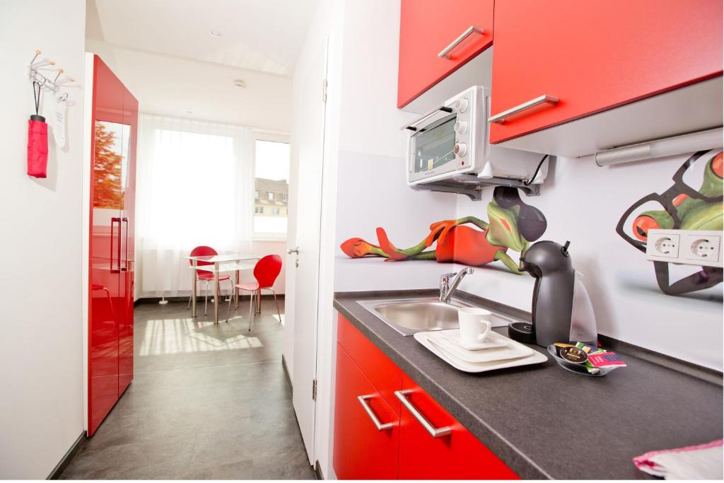 科隆设计斯利普公寓式酒店的一间带红色橱柜和水槽的厨房