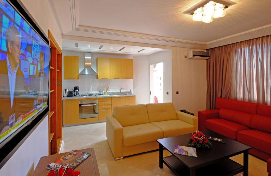 马拉喀什莫纳公寓式酒店的一间带红色沙发的客厅和一间厨房