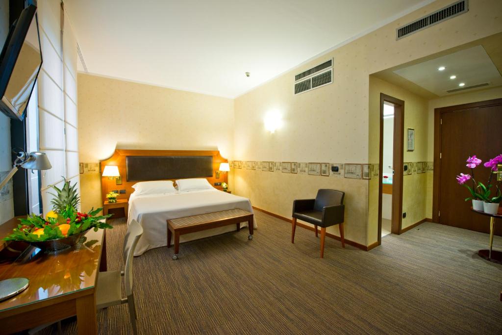 米兰德埃斯特酒店的酒店客房配有一张床、一张桌子和一把椅子。