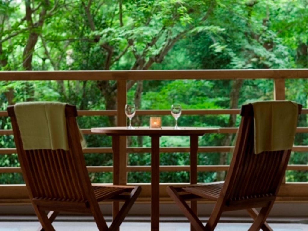 箱根箱根小涌谷温泉水之音传统日式旅馆的门廊上的两把椅子和一张桌子,上面摆放着酒杯