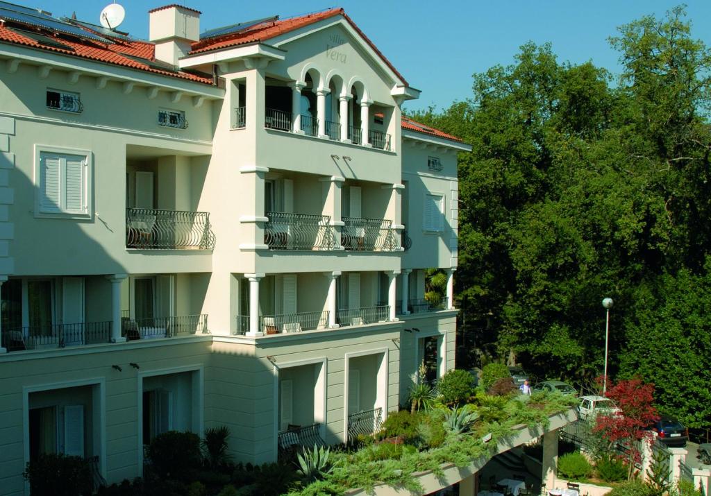 洛夫兰维拉别墅酒店 的一座大型白色建筑,设有阳台和树木