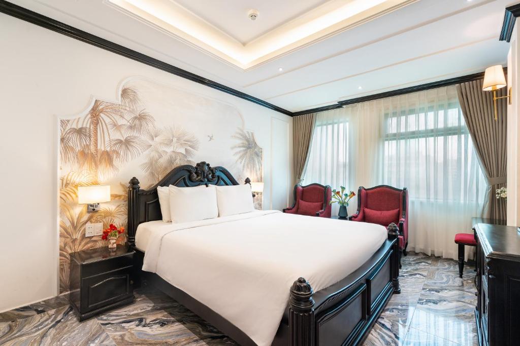 胡志明市Nicecy Saigon Hotel的酒店客房,配有一张床和两张红色椅子