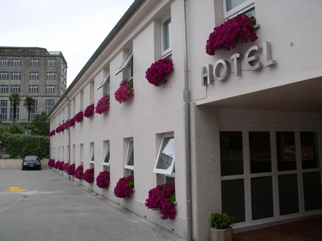 圣地亚哥－德孔波斯特拉Hotel Parking Miradoiro de Belvís的一座建筑的一侧,有粉红色花卉的酒店