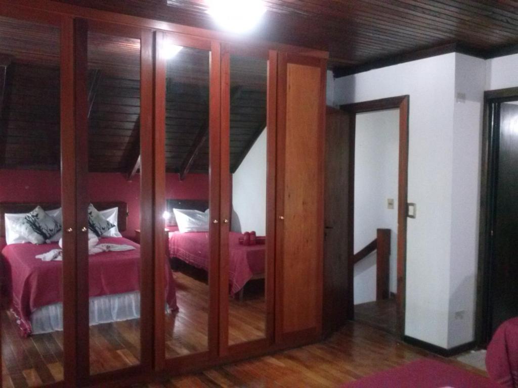 伊瓜苏港Petit Hotel Caraguata的卧室配有粉红色的床和玻璃门