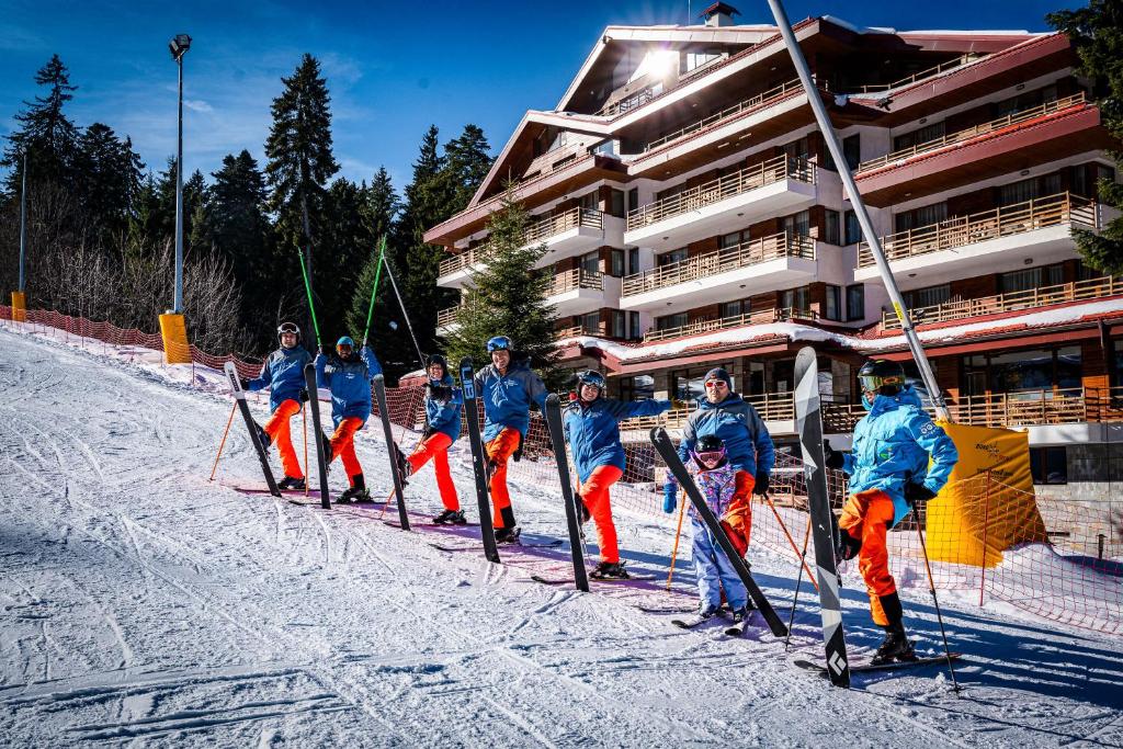 波罗维茨Musala Hotel的一群人坐在大楼前的雪地里