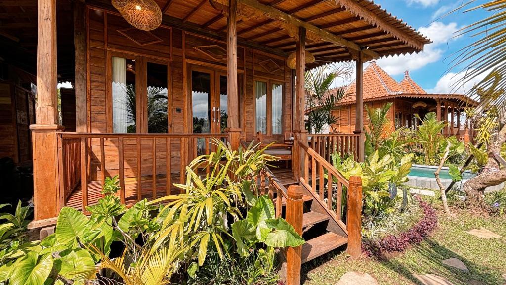 乌布Jagadhita Villas Ubud Bali的木屋设有门廊和游泳池